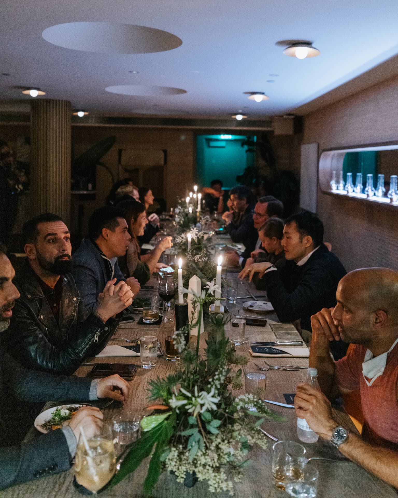 Long candlelit dinner table with guests in conversation