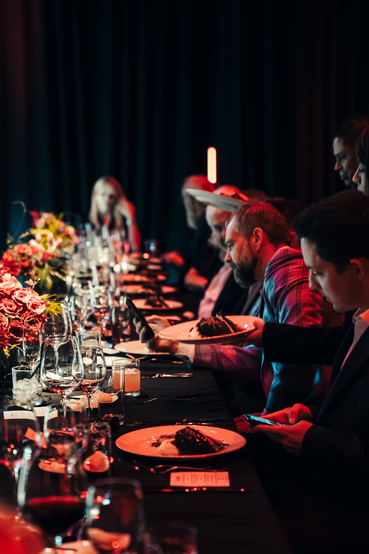 Guests seated for a red-lit private dinner