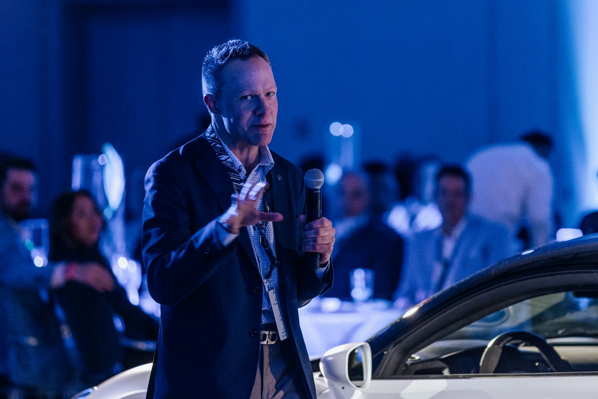 Speaker presenting beside a sports car