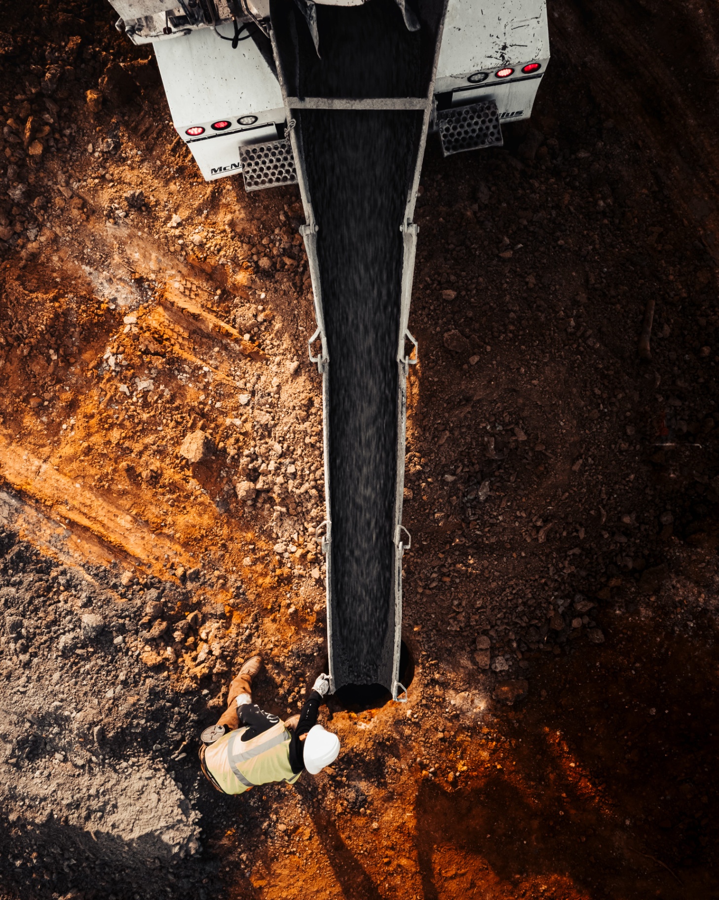 Aerial view of worker guiding gravel pour from truck