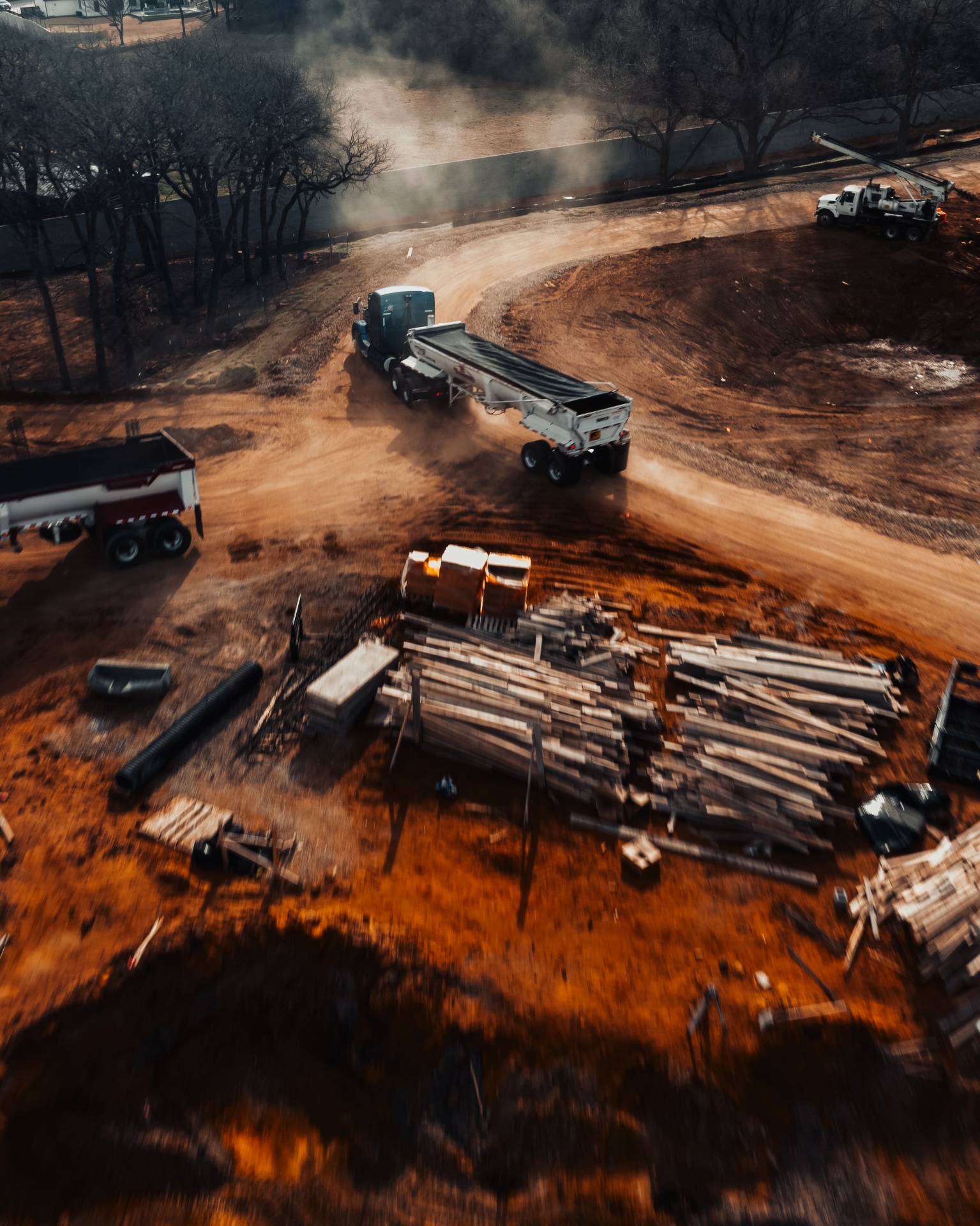 Aerial view of dusty construction site with trucks and lumber