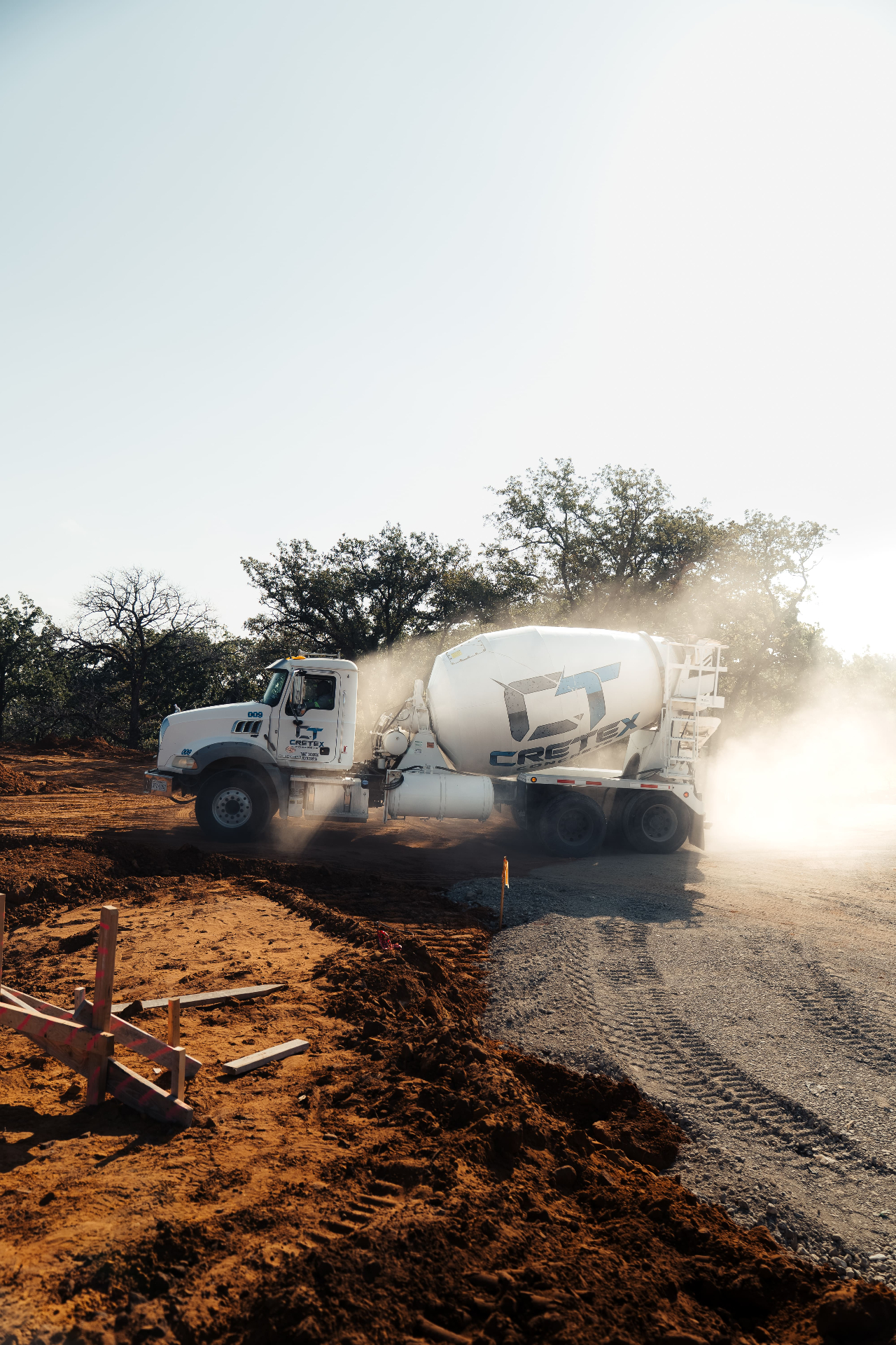 Concrete mixer truck backlit by sun on dirt road
