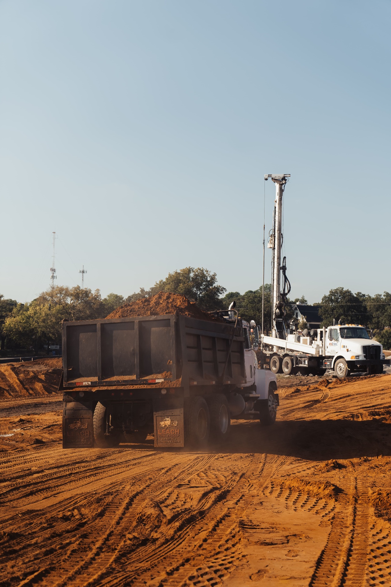 Dump truck and drill rig on graded construction site
