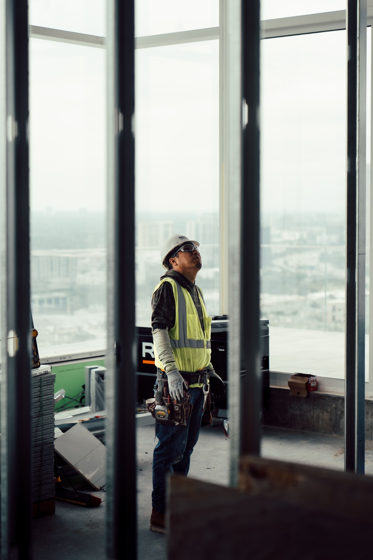 Worker standing inside framed interior near window wall