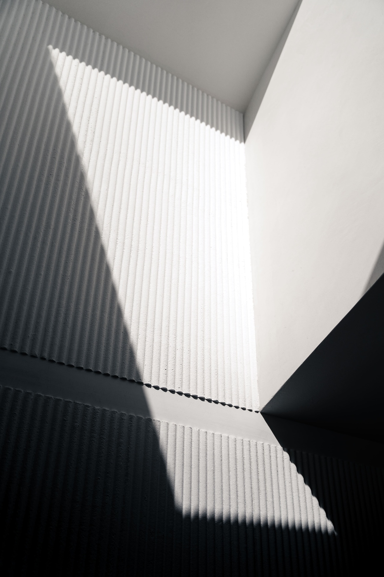 Fluted plaster wall with dramatic diagonal light and shadow