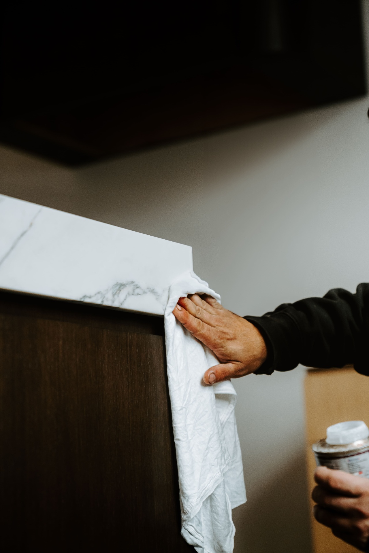 Hand wiping marble countertop edge during install