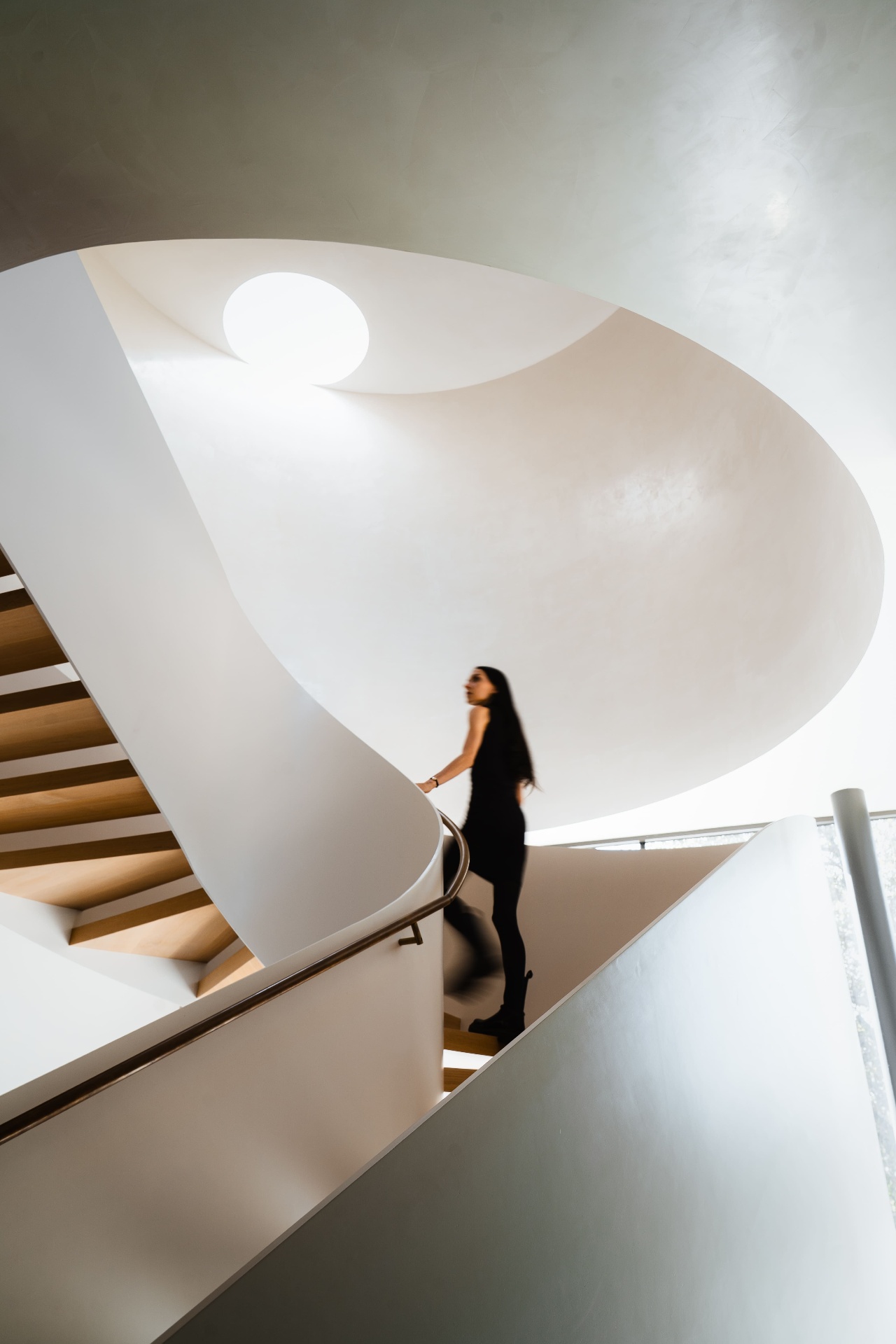 Woman ascending sculptural spiral staircase