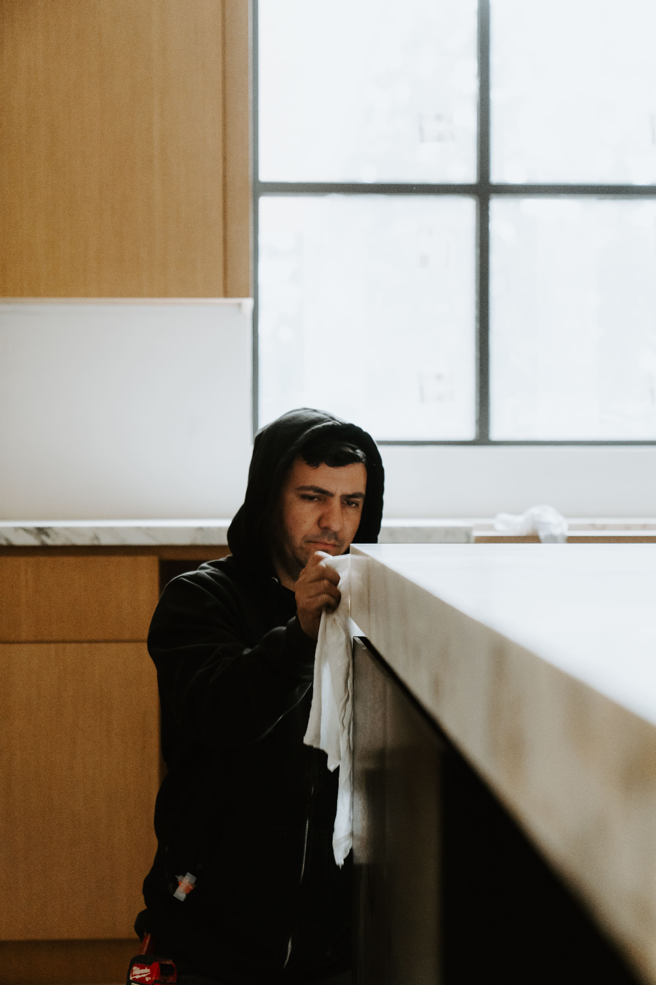 Worker cleaning marble counter by window
