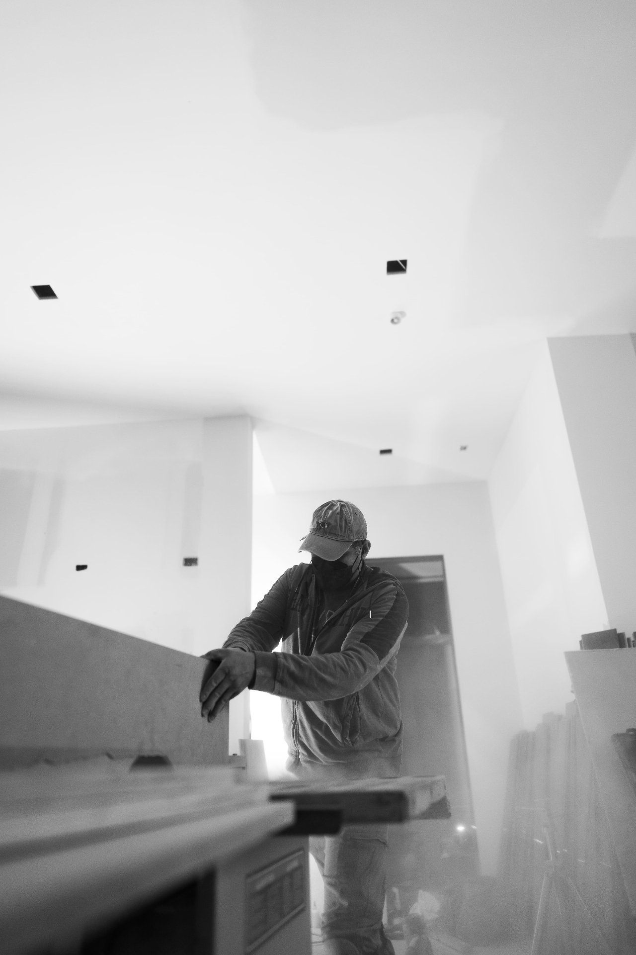 Worker finishing drywall in high-ceiling interior