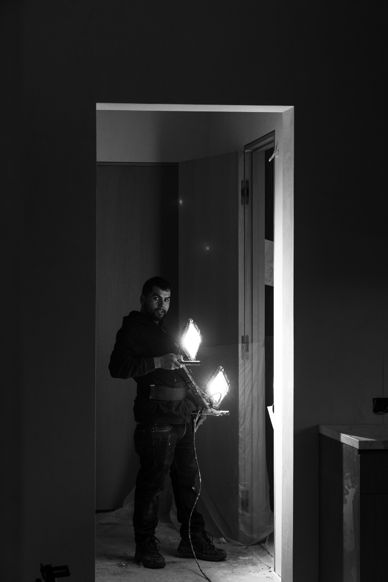 Worker carrying light fixtures through doorway
