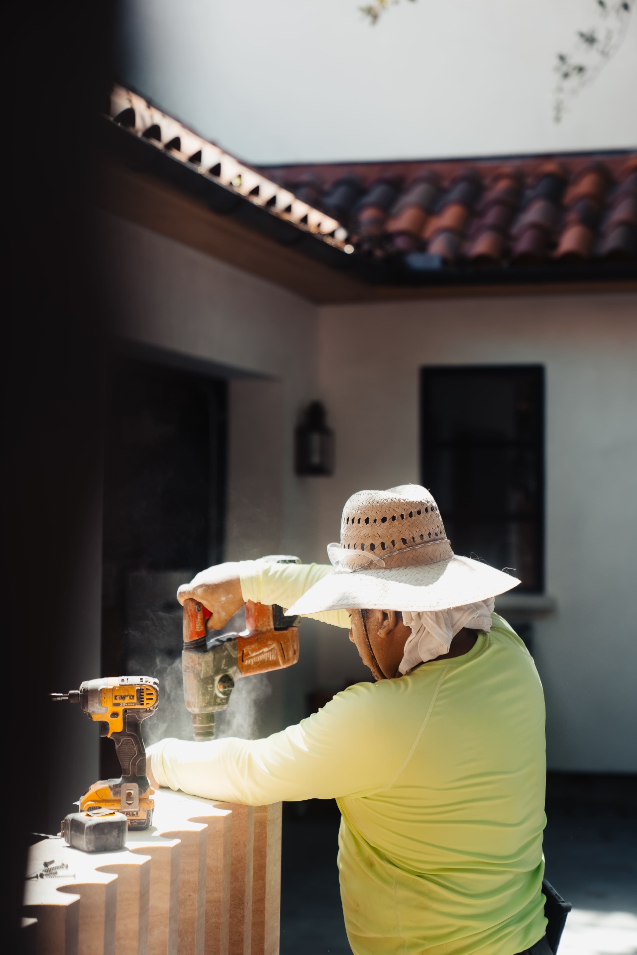 Worker with hat drilling fireplace stone on site